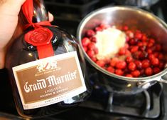 a bottle of grand marnier liqueur next to a pot of cranberries