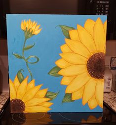 a painting of two yellow sunflowers on a blue background