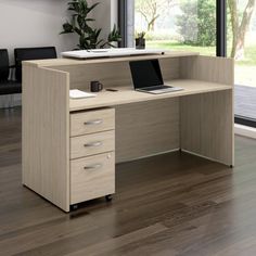 an office desk with a laptop on it in front of a large window and wooden floors