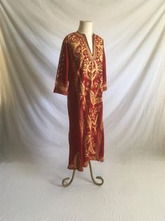 1970s handmade kaftan shirt dress red velvet gold color brocade w/silver accenting thread deep v pullover 3/4 sleeve ankle length, depending on wearer's height 7" side slits good vintage condition, light wear light irregularities normal to handmade item no size tag, see below measures, lying flat, shoulder-17" sleeve-17" chest-21 1/2" waist-19" hip-22" length-51"     We do not offer returns or refunds unless something is grossly misrepresented. Please contact us within 2 business days of receivi Festive Red Kaftan With Gold Embroidery, Bohemian Gold Long Thobe, Gold Long Bohemian Thobe, Bohemian Long Sleeve Gold Kaftan, Gold Long Sleeve Bohemian Kaftan, Gold Bohemian Long Sleeve Kaftan, Bohemian Long Gold Kaftan, Gold Bohemian Kaftan For Festival, Long Bohemian Gold Kaftan