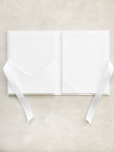 an open book with white paper tied to it's sides and ribbon around the pages