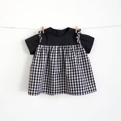 a black and white checkered dress hanging on a clothes line with two pegs