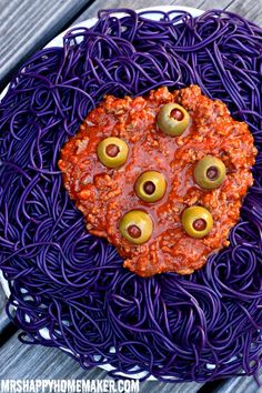 purple spaghetti with olives and meatballs in the shape of a heart on top