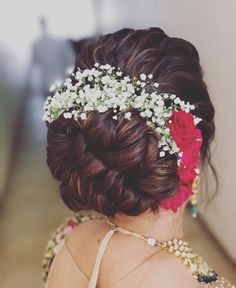 the back of a woman's head with flowers in her hair and pearls on it