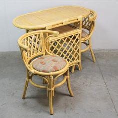 three wicker chairs and a table with a cushion on it in front of a white wall