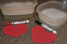 two heart shaped paper cutouts sitting on top of a counter next to a container