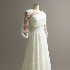 a white wedding dress with long sleeves and flowers on it