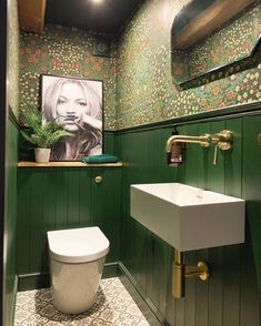 a bathroom with green walls and floral wallpaper on the walls, along with a white toilet and sink