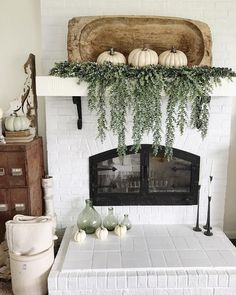 a living room with a white brick fireplace and lots of greenery on the mantle