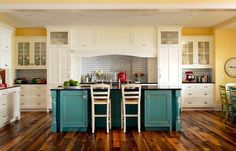 an open kitchen with white cabinets and blue counter tops, hardwood floors, and yellow walls