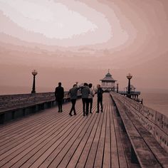 several people walking on a boardwalk near the ocean