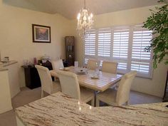 a dining room table with white chairs and a chandelier