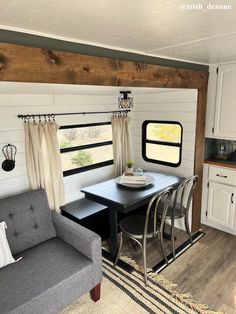 a living room and dining area in a mobile home with white walls, wood flooring and windows