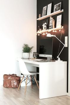 a white desk with a computer on top of it next to a brown bag and some pictures