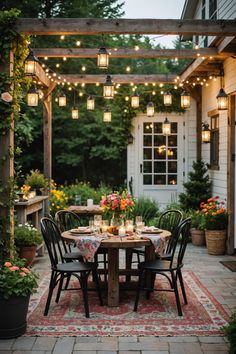 an outdoor dining area with lights strung over the table and chairs, surrounded by potted plants