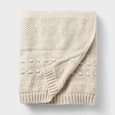 a white knitted blanket folded on top of a table