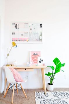 a room with a desk, chair and potted plant on the floor in front of it