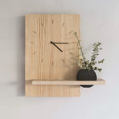 a wooden clock mounted to the side of a wall next to a vase with flowers