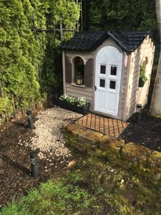 a small house in the middle of a forest with trees around it and gravel path leading up to it