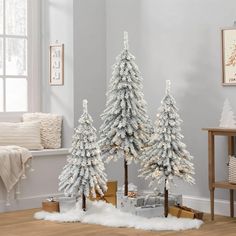 three white christmas trees in a living room