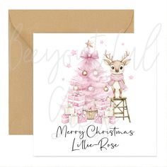 a card with a pink christmas tree and presents on it, in front of a brown envelope