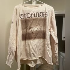 a white long sleeved shirt hanging on a clothes rack