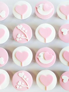 the cupcakes are decorated with pink and white icing, including heart shapes