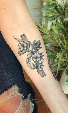 a woman's arm with a tattoo on it that has flowers and a ribbon