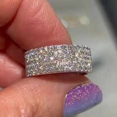 a woman's hand holding a ring with two rows of diamonds on top of it