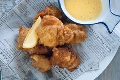 some fried food is on a plate next to a bowl of mustard and a glass of orange juice