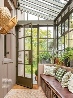 a sun room with lots of windows and plants on the bench in front of it