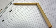 a pencil laying on top of a piece of graph paper with holes in the middle