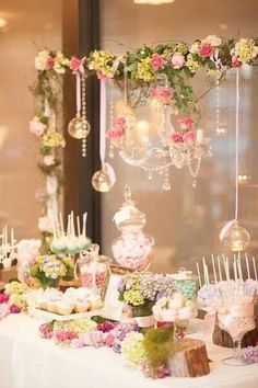 a table topped with lots of desserts and candies next to a wall covered in flowers