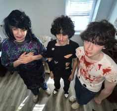 three people standing in a room with blood all over them