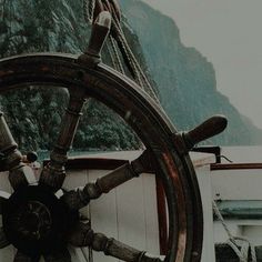 the steering wheel of a ship with mountains in the background