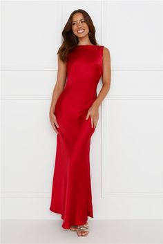 a woman in a red dress standing against a wall with her hands on her hips