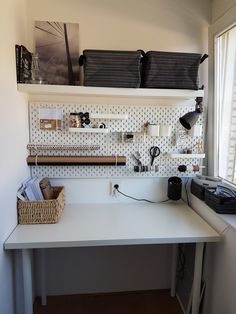 a white desk topped with lots of items next to a wall mounted shelf filled with books