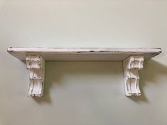 an old white shelf with decorative brackets on it