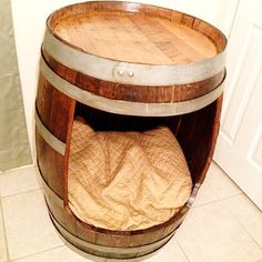 a wooden barrel sitting on top of a floor next to a bed inside of it