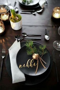 a table set with black plates, silverware and napkins for an elegant christmas dinner