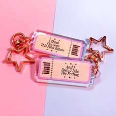 two keychains with tags attached to them on a pink and blue background that says, i think i need this little bow