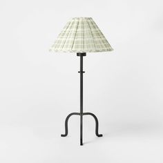 a lamp that is sitting on top of a metal stand with a white and black shade