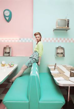 a woman sitting on top of a blue bench in a room with pink and green walls