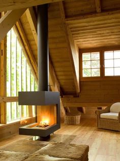 a living room filled with furniture and a fire place in the middle of a wooden floor