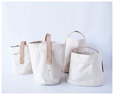 three white canvas bags with leather handles