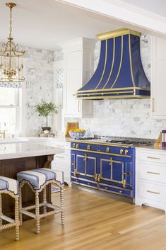 a kitchen with blue and gold appliances in the center, white cabinets and wood floors