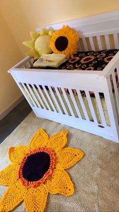 a crocheted sunflower rug sits next to a white crib