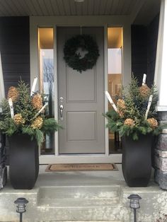 two large planters on the front steps of a house with wreaths and lights