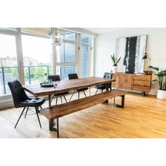 a dining room table with two benches in front of it and large windows overlooking the city