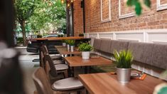 tables and chairs are lined up against the brick wall in this outdoor dining area with potted plants